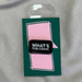 rectangular black pin with Whats the Craic in white block letters on a pink and green backing board