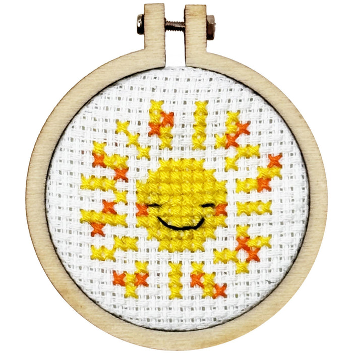 Cross-stitched smiley face design in a wooden hoop on a white background