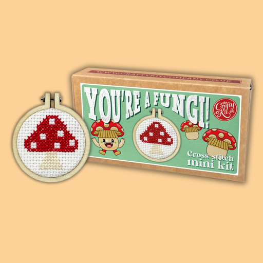 Cross-stitch mini kit with mushroom design and packaging labeled 'You're a Fungi!' on a beige background.
