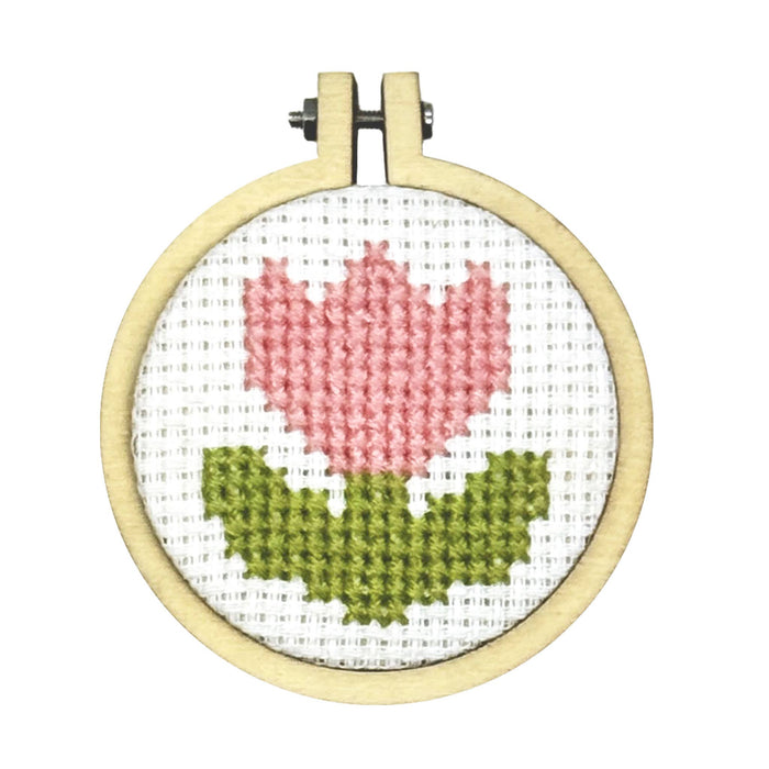 Crosstitch piece in circular hoop with pink flower on white background