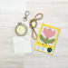 embroidery hoop, keychain, fabric & crosstitch pattern card on a wooden surface