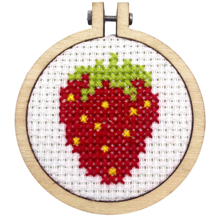 Cross-stitched strawberry design in a wooden hoop on a white background