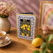 Greeting card with lemons and 'sending sunshine' text on a table with a lemon, teacup, and flowers.