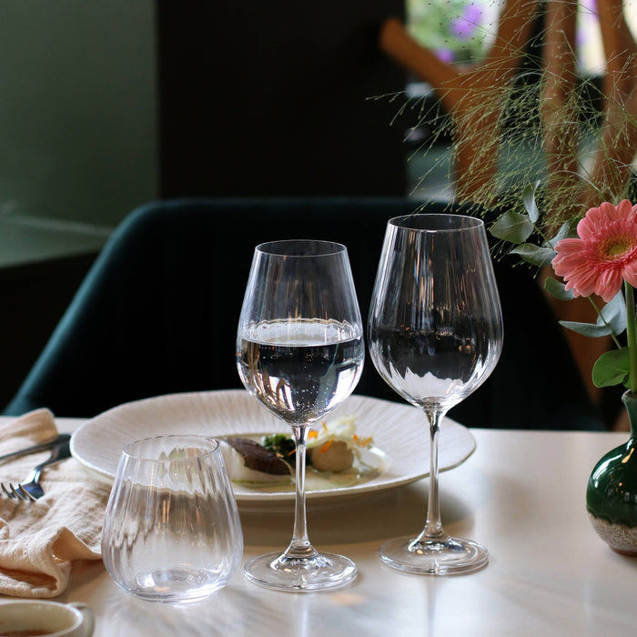 Three wine glasses with water on a table with a blurred background
