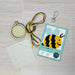 Cross-stitch kit with hoop, thread, pattern chart, and keychain on a wooden surface