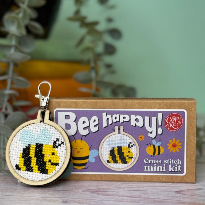 bee happy cross stitch keyring kit and oackaging against a green background