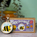 bee happy cross stitch keyring kit and oackaging against a green background