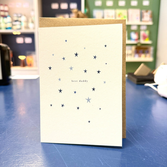 Greeting card with star pattern and 'best daddy' text on a blue surface