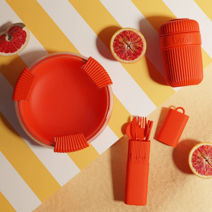 Red silicone utensil holder with cut oranges on a striped background