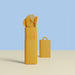 Mustard yellow cutlery set in a holder on a beige surface with a light blue background