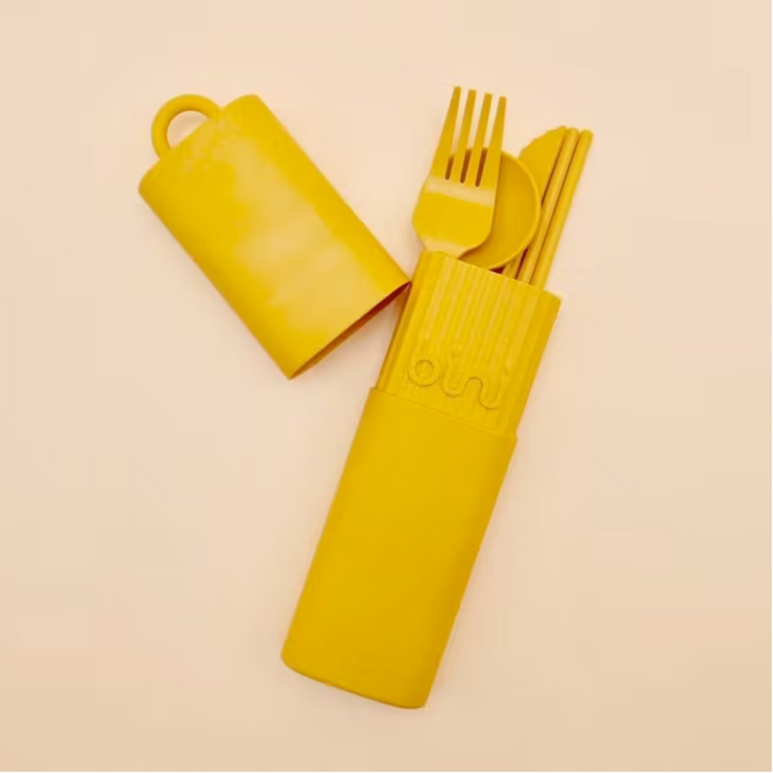 Yellow cutlery set with holder on a beige background