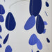 A mobile or wall hanging made of hanging teardrop-shaped paper cutouts in shades of blue and navy on thin strings, photographed against a plain light background.
