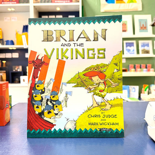 The children's book 'Brian and the Vikings' by Chris Judge and Mark Wickham stands upright on a blue counter in a retail store. The cover features a colorful illustration of a Viking warrior with red hair and a horned helmet holding a bow, standing next to a longship with yellow-skinned Vikings wearing blue helmets.