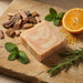 Bar of soap on a stone surface with herbs and an orange slice
