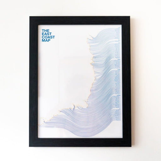A framed art print titled 'THE EAST COAST MAP' featuring layered blue and purple line patterns on a white background, enclosed in a black frame and mounted on a light wall.
