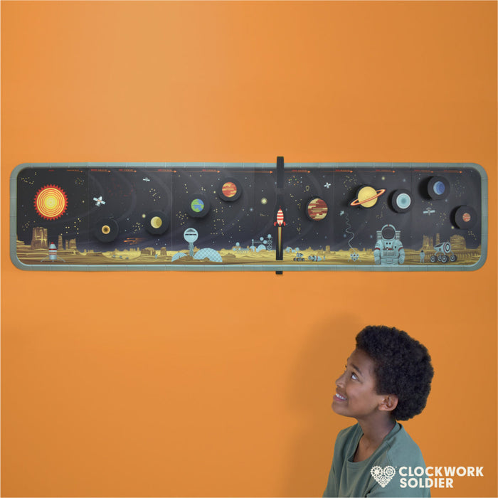 Child looking at a create-your-own solar system paper craft kit with various planets and a sun illustration on it.