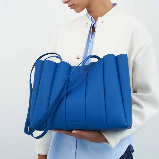 Person holding a blue bag against a plain background