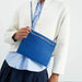 Person wearing a white jacket and blue shirt with a blue pouch on a white background