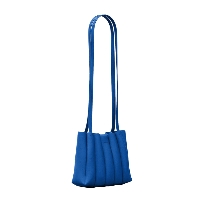A vibrant blue shoulder bag with a structured, pleated design and a single long strap, shown against a plain white background.