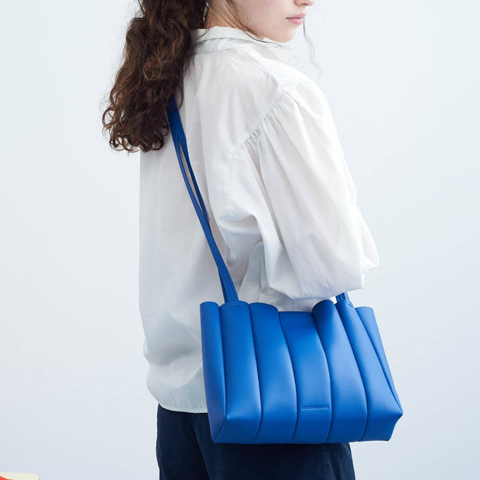 Woman carrying a blue bag on a plain background