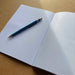 Blue pen on an open notebook with a plain background