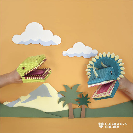 two dinosaur puppets being played with with a cut out paper landscape background