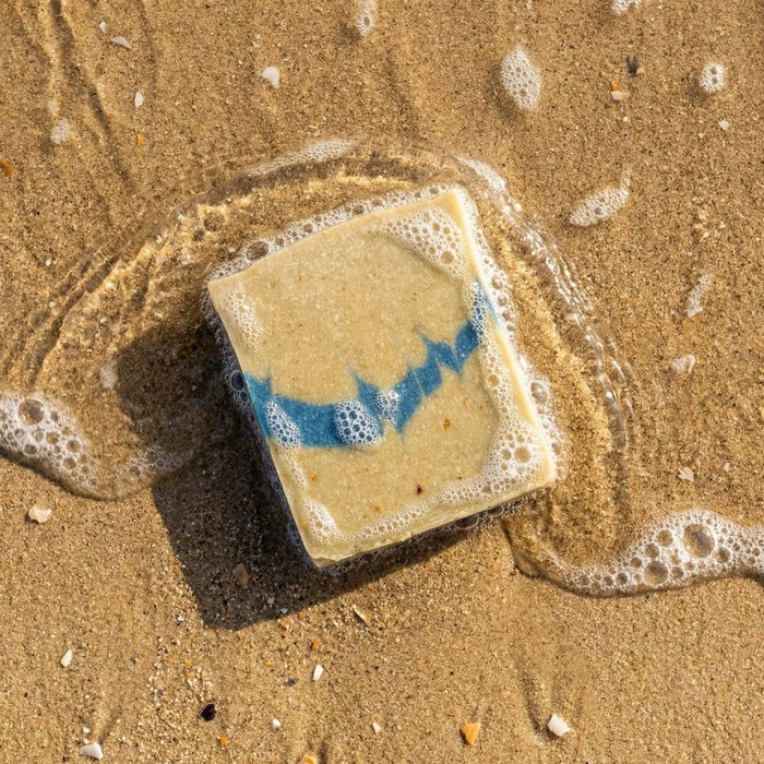 Square bar of soap with blue design on sand