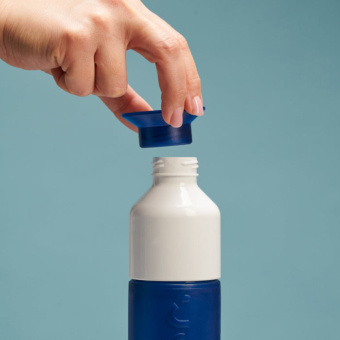 Hand opening a blue and white bottle cap against a light blue background
