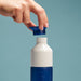 Hand opening a blue and white bottle cap against a light blue background