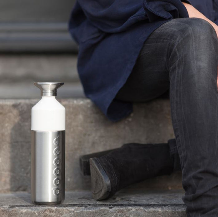 Person sitting on steps with a white and silver water bottle next to them