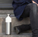 Person sitting on steps with a white and silver water bottle next to them
