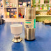 Silver Dopper bottle with a white cup on a blue surface, with a store interior in the background.