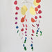 A hanging mobile with thin metal arches and dangling paper shapes in yellow, orange, pink, purple, blue, and green on a plain light background.