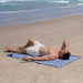 Man lying on a striped beach towel at the beach with ocean waves in the background