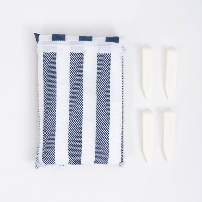 White drawstring bag containing a towel with blue and stripes beside four cream coloured clips on a white background