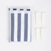 White drawstring bag containing a towel with blue and stripes beside four cream coloured clips on a white background