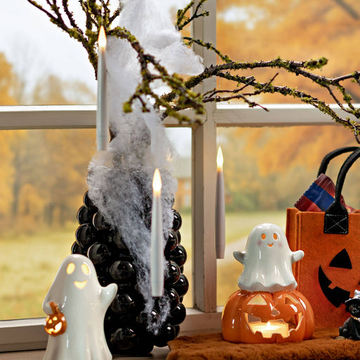 Halloween decorations including a black decorative object with white smoke, ghost figurines, and a pumpkin-shaped lantern.