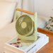 Portable fan on a stack of books with a cozy indoor setting
