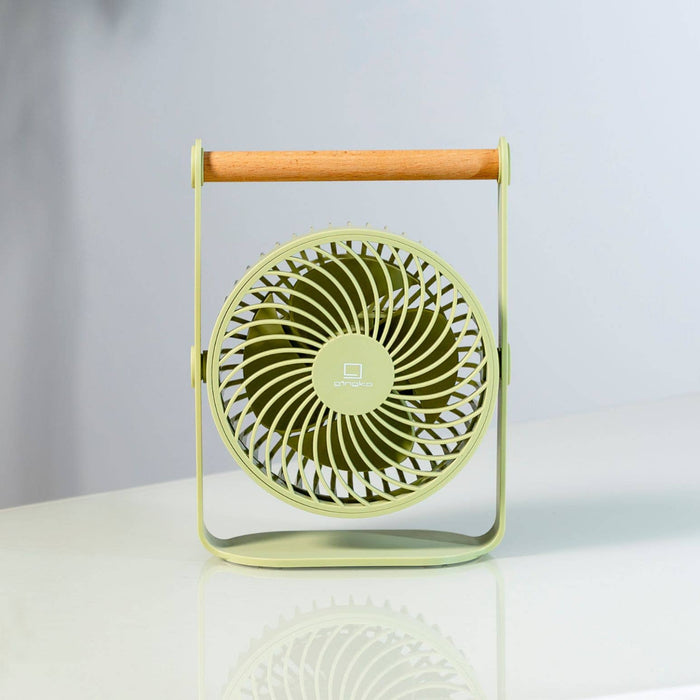 Green portable fan on a white surface with a blurred background