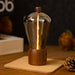 Bulb shaped lamp on a wooden coaster with blurred background.