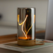 Glass lamp with glowing interior on a wooden surface.