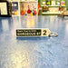 Keychain with text 'Sure You're Only GORGEOUS ST' on a blue surface