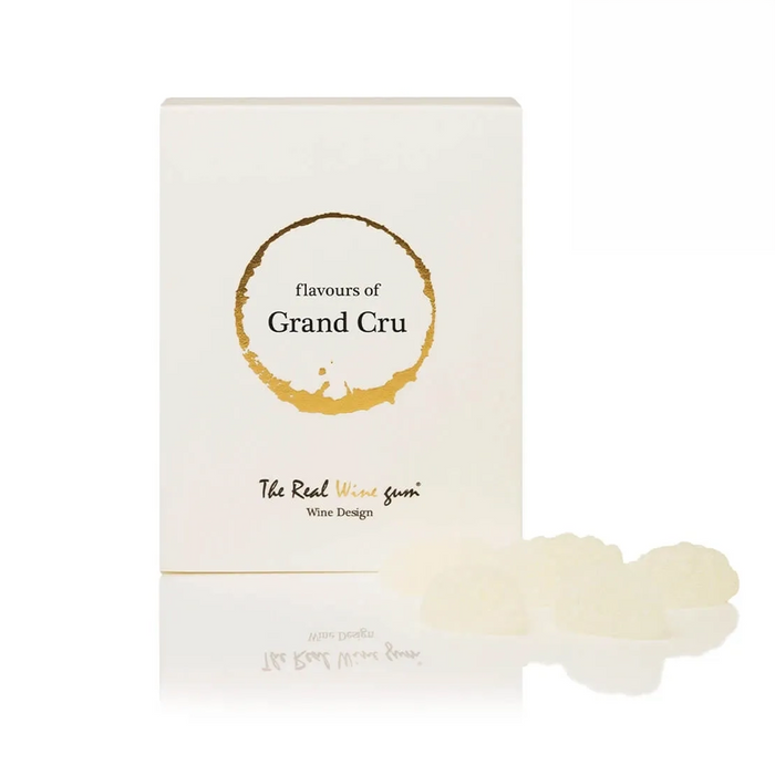 A white rectangular box labeled 'flavours of Grand Cru' with a gold wine-stroke graphic and 'The Real Wine gum' branding, shown on a white background with several translucent off-white gum pieces in front.