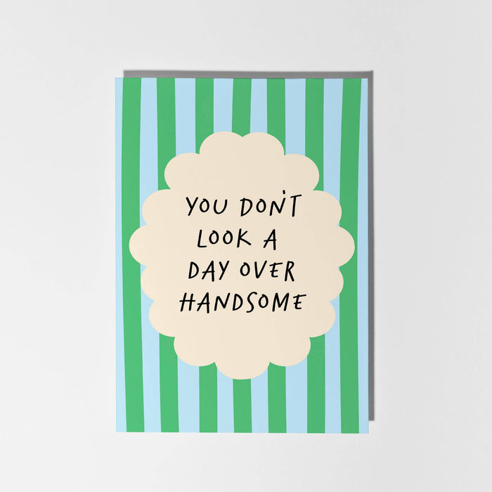 Card with green and blue striped design and text 'You don't look a day over handsome'.