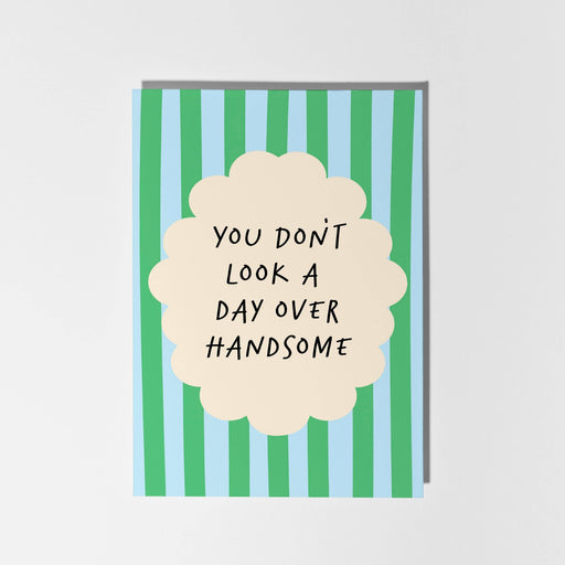Card with green and blue striped design and text 'You don't look a day over handsome'.