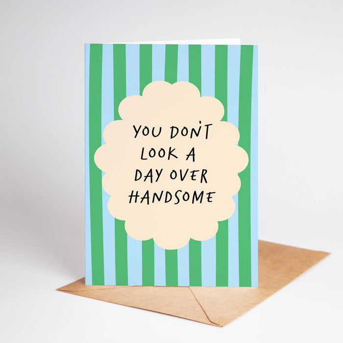 Greeting card with striped design and text 'You don't look a day over handsome' on a white background.