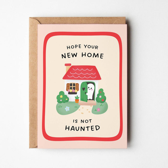 Greeting card with cartoon cat, house, and text 'Hope your new home is not haunted' on a white background