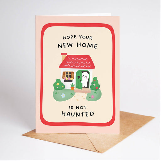 Greeting card with a cartoon house and text 'Hope your new home is not haunted' on a light pink background.