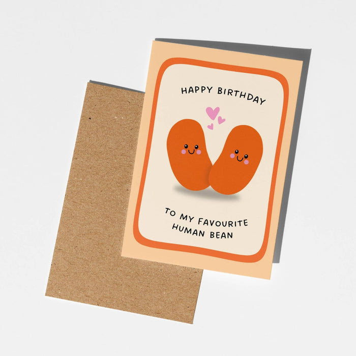 A birthday greeting card with a kraft envelope, featuring an illustration of two smiling orange beans with pink hearts and the text 'HAPPY BIRTHDAY TO MY FAVOURITE HUMAN BEAN'.