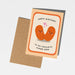 A birthday greeting card with a kraft envelope, featuring an illustration of two smiling orange beans with pink hearts and the text 'HAPPY BIRTHDAY TO MY FAVOURITE HUMAN BEAN'.